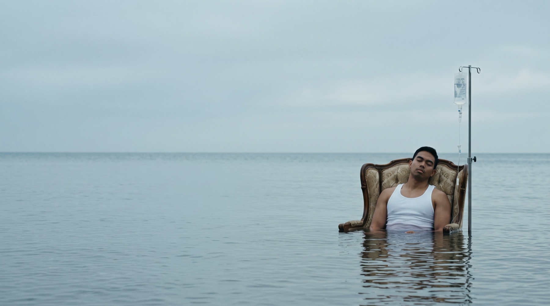 Seated in an armchair in the sea beside an IV stand